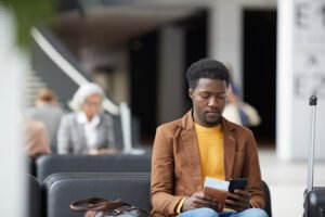 Traveller using phone at airport - essential travel apps for slow travel