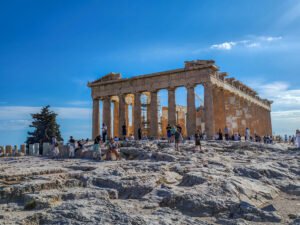 The Parthenon on the Acropolis Hill, slow travel Athens Greece — visitors exploring the ancient marble site under a clear blue sky