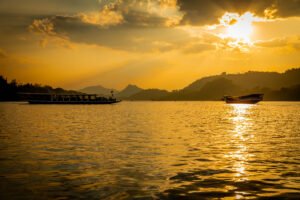 Sunset cruise on the Mekong River, Luang Prabang slow travel Laos — silhouetted longboats against a golden sky