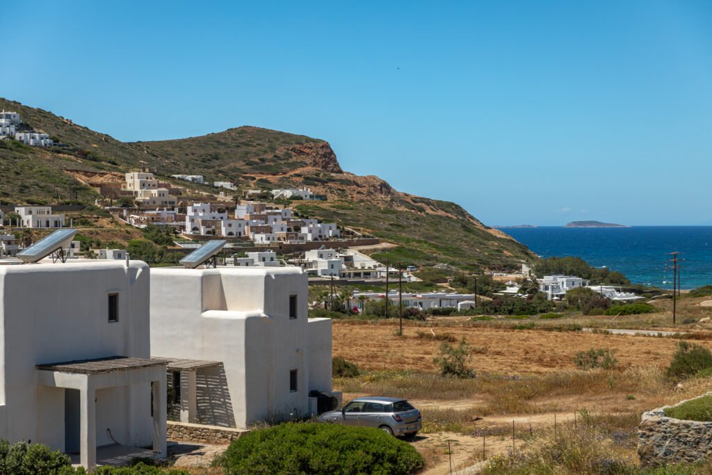 Whitewashed Cycladic villas overlooking the coastline in Stelida, slow travel Naxos Greece — blue Aegean Sea in the background