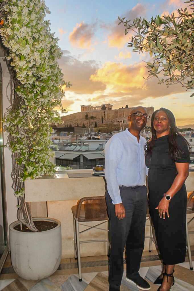 Mike and Marge at Stork Rooftop Bar, slow travel Athens Greece — Acropolis illuminated at sunset in the background