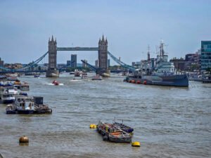 Tower Bridge open over the River Thames with HMS Belfast moored alongside, London